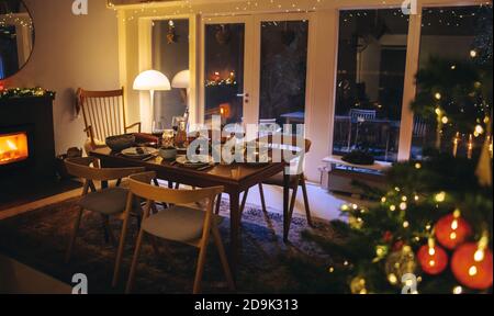 Innenaufnahme eines Familienhauses, das für Weihnachtsfeierlichkeiten dekoriert ist. Esstisch für Abendessen am Heiligabend im Innenbereich. Stockfoto