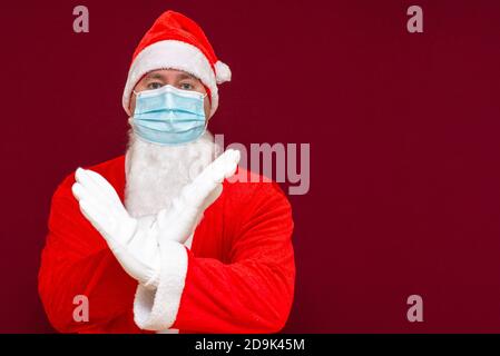 Nahaufnahme weihnachtsmann Kostüm Ablehnung Ausdruck Kreuzung Arme und Handflächen tun negative Zeichen, trägt medizinische Maske.Vorderansicht Bild. Stockfoto