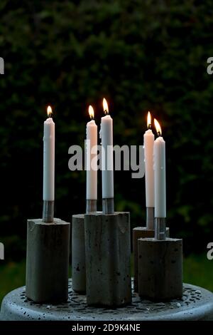 Weiße lange Kerzen mit Leuchtern aus Beton Stockfoto