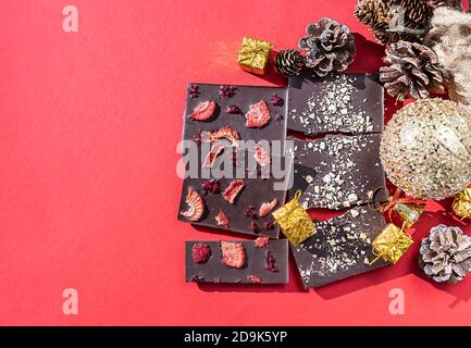 Handgemachte Schokoriegel mit Beeren auf einem weihnachtlichen Hintergrund. Blick von oben. Stockfoto