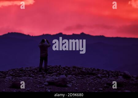 Unglaubliche lila Sonnenuntergang in den Bergen. Farben der Natur. Sonnenuntergangspanorama auf dem Hintergrund der Berge. Tourist macht Bilder von der Landschaft Stockfoto