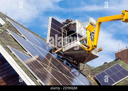 Arbeiter installieren Sonnenkollektoren auf privaten Haus sechseckigen Dach fühlte sich an sonnigen Tag, blauer Himmel. Leben. Heimkraftwerk. Stockfoto
