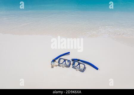 Zwei Masken und Schnorchelausrüstung in den Wellen des Sandstrandes. Exotische Outdoor-Sport-Aktivität, Freizeit-Hobby. Blick auf den Strand und die Landschaft Stockfoto