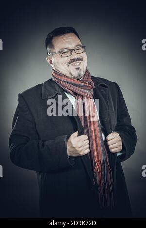 Solider fröhlicher Mann in Brillenmantel und Einstecktuch emotionales Studio Hochformat Stockfoto