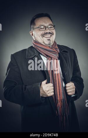 Solider fröhlicher Mann in Brillenmantel und Einstecktuch emotionales Studio Hochformat Stockfoto