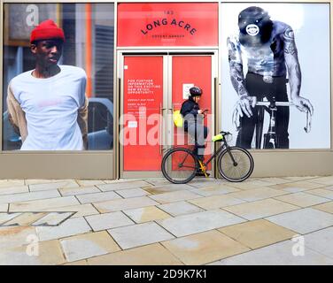 London, England, Großbritannien. Junger Mann, der sich in Long Acre, Covent Garden, auf seinem Fahrrad ausruhte und sein Handy überprüfte Stockfoto