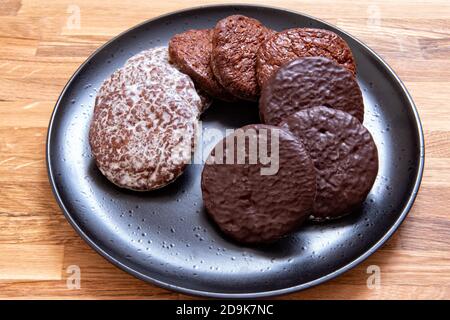 Drei Arten von deutschen runden Lebkuchen auf schwarzem Teller. Lebkuchen mit Schokolade überzogen. Weihnachtliche Wüste, Snack. Stockfoto