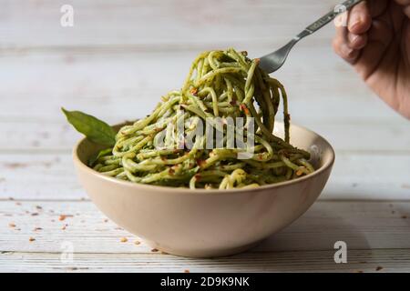 Pasta in Pesto-Sauce wird aus einer Schüssel zusammen serviert Auf einem Hintergrund Stockfoto