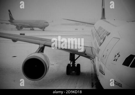 Schwarz-Weiß-Ansicht eines Flugzeugs, das auf Passagiere nach Βoard wartet. JFK Airport an einem verschneiten Tag. New York City, USA Stockfoto