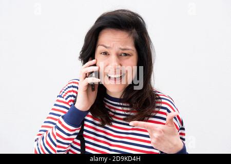 Nahaufnahme Porträt verwirrt junge Frau im Gespräch mit Handy gegen Isolierter weißer Hintergrund Stockfoto