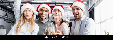 Fröhliche multiethnische Geschäftsleute in santa Hüte Toasting mit Champagner, Banner Stockfoto