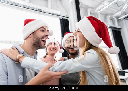 Lächelnde, multiethnische Geschäftsleute, die Weihnachten im Büro feiern Stockfoto