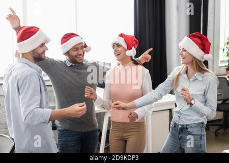 Positive multiethnische Geschäftsleute in santa Hats feiern Neujahr in Büro Stockfoto