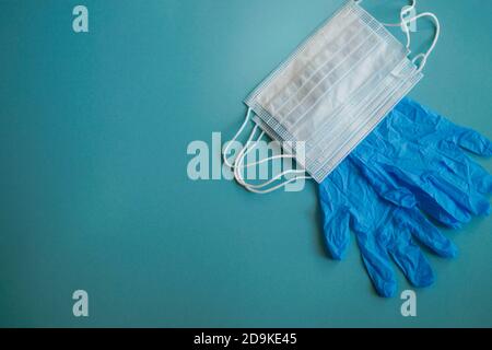 Ein Paar dünne blaue medizinische Latexhandschuhe und eine Schutzmaske auf blauem Hintergrund. Medizinische Einweghandschuhe aus Gummi und Maske. Schutzelemente. Sonstiges Stockfoto