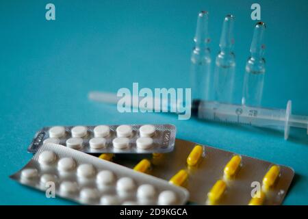 Medizinische Ampullen, Pillen und eine Spritze auf blauem Hintergrund Stockfoto