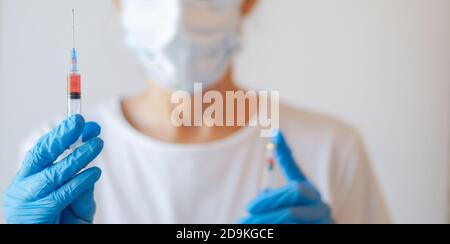 Nahaufnahme eines nicht erkennbaren Arztes mit Schutzmaske und Handschuhe mit Spritze und Covid-19-Impfstoff Stockfoto