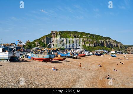 Die Küstenlinie bei Hastings, an der Ostküste Sussex, Südengland, mit beachzten Fischerbooten und East Hill im Hintergrund Stockfoto