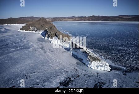 Gefrorener Baikalsee, Kap Horin-Irgi der Olchon Insel. Schöne Winterlandschaft mit klarem glatten Eis in der Nähe felsigen Ufer. Das berühmte Naturdenkmal Stockfoto