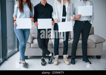 Vorderansicht der jungen Gruppe von Freunden, die leer halten Papiere in den Händen Stockfoto