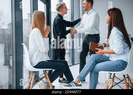 Erfolgreiche Vereinbarung. Handshake. Gruppe von jungen erfolgreichen Team, dass die Arbeit und Kommunikation zusammen drinnen im Büro Stockfoto