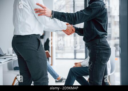 Erfolgreiche Vereinbarung. Handshake. Gruppe von jungen erfolgreichen Team, dass die Arbeit und Kommunikation zusammen drinnen im Büro Stockfoto