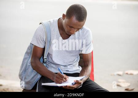 Junger Student, ein Mann, der nach der Schule in der Stadt sitzt Stockfoto