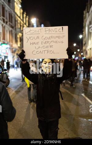 Porträt eines marschierenden Protestierenden in Guy Fawkes Maske und Plakat halten während der Million Mask March von vielen Lockdown Skeptiker besucht, London, 5 Nein Stockfoto
