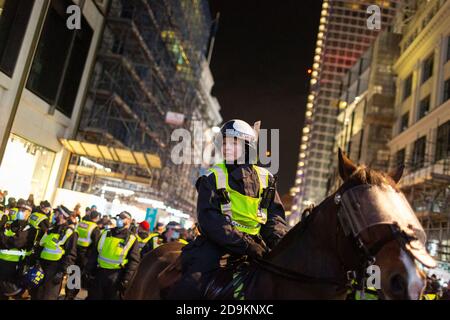 Ein Polizist zu Pferd vor ketteten Demonstranten während des Millionen-Maske-Marsches, an dem viele Lockdown-Skeptiker teilnahmen, London, 5. November 2020 Stockfoto