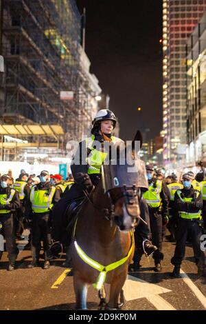 Ein Polizist zu Pferd vor ketteten Demonstranten während des Millionen-Maske-Marsches, an dem viele Lockdown-Skeptiker teilnahmen, London, 5. November 2020 Stockfoto