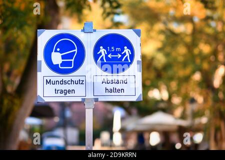 Schilder für Gesichtsmaske und Abstand Anforderung in deutscher Stadt Zentriert mit Text „Gesichtsmaske tragen“ und „Abstand halten“ Stockfoto