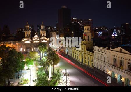 Blick auf Plaza de Armas Hauptplatz der Stadt Santiago de Chile bei Nacht. Langzeitbelichtung mit verschwommenen Autoleuchten. Kathedrale Von Santiago Stockfoto