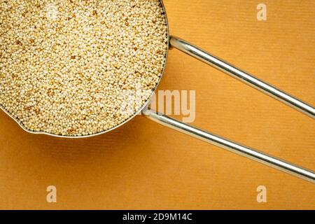 Glutenfreies Elfenbein-Teffkörner in einem Messlöffel aus Metall, Draufsicht gegen handgemachtes Lapppapier, wichtiges Lebensmittelkorn in Äthiopien und Eritrea Stockfoto