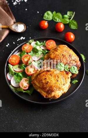 Gebratene Hähnchenschenkel mit Gemüse auf dem Teller Stockfoto