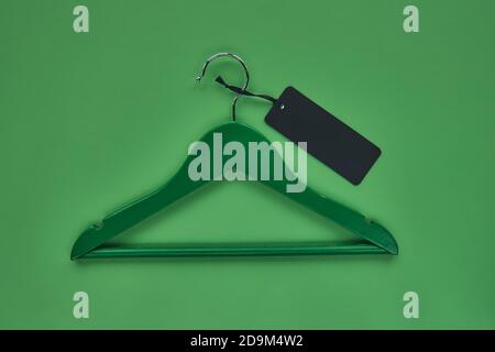 Holzhänger mit schwarzem Papieretikett isoliert auf grünem Papierhintergrund. Nahtlose Muster Mockup Vorlage, um Ihr Design zu platzieren. Black friday Finale Stockfoto