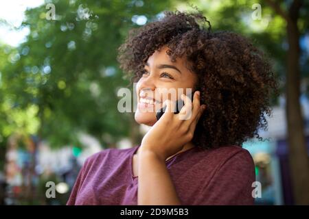 Nahaufnahme Seitenportrait schöne junge afroamerikaner im Gespräch mit Handy draußen Stockfoto