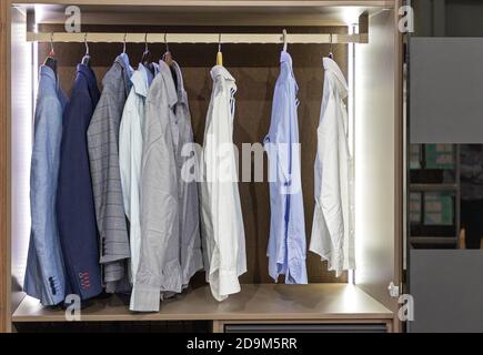 Business Shirts und Anzüge an Kleiderbügeln im Kleiderschrank Stockfoto