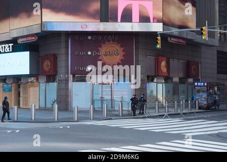 Zwei maskierte Polizisten stehen vor einem geschlossenen Europa Cafè auf dem Times Square. Stockfoto