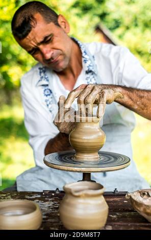 Sibiu City, Rumänien - 26 juli 2019. Hände eines Töpfers, der einen Tontopf auf einem Töpferrad auf der Töpfermesse aus Sibiu, Rumänien, formt Stockfoto