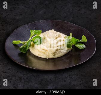 Portion Kartoffelpüree in schwarzer Platte, dunkler Hintergrund. Stockfoto