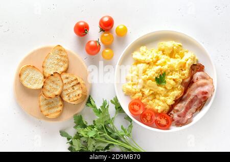 Rührei und Tomaten auf dem Teller über hellem Steingrund. Draufsicht, flacher Lay Stockfoto