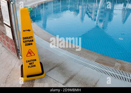 Belek, Türkei - Oktober 2020: Sicherheitsmaßnahmen in einem Luxushotel. Warnschild über nassen Boden in der Nähe eines Schwimmbades. Vorsicht auf rutschigem Untergrund Stockfoto