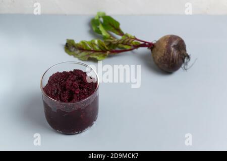 Rübenkonfitüre in einem Glas mit frischen Rüben auf grauem Hintergrund. Gesunde Ernährung Konzept. Speicherplatz kopieren. Selektiver Fokus. Stockfoto