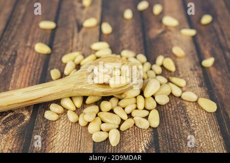 Pinienkerne mit einem Holzlöffel auf einem hölzernen Hintergrund Stockfoto