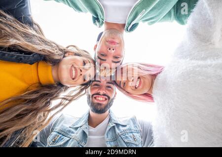 Gruppe von vier Teenagern, die im Arm nach unten schauen - Multikulturelle Gruppe junger Leute, die Spaß haben - Friends on Sommerurlaub Blick auf Kamera und la Stockfoto