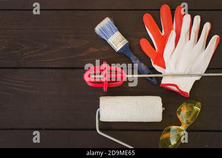 Gegenstände und Werkzeuge des professionellen Malers auf Holzhintergrund. Maler und Dekorateur Arbeitstisch, Schneebesen zum Mischen von Farbe, Handschuhe, Malerrolle und pa Stockfoto