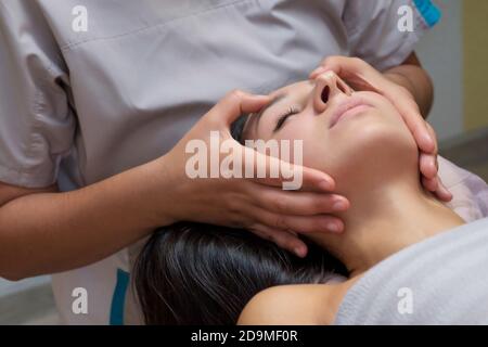Schöne Frau in Massage Salon erhalten Gesichtsmassage. Stockfoto