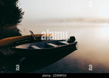 Leeres Dock mit festgebundenen Booten an einem nebligen Morgen auf einem ruhigen See. Stockfoto