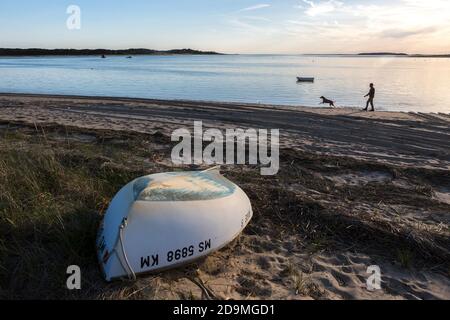 Ein Boot auf dem Kopf am Strand mit Mann zu Fuß Hund in Wellfleet, MA Stockfoto