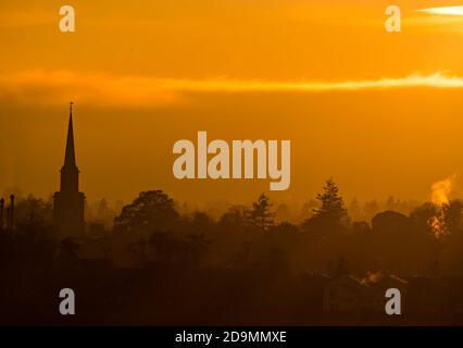 East Lothian, Schottland, Großbritannien, 6. November 2020. Wetter in Großbritannien: Ein trüber Sonnenuntergang schafft einen nebligen Blick über die Skyline von Haddington mit dem Turm des Haddington Town House, der vor einem orangen Himmel sichtbar ist Stockfoto