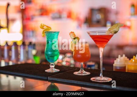 Bunte Cocktails an der Bar. Tropische Cocktails auf dem Restauranttisch, fertig zum Servieren. Nachtleben Party, Bar Drink Hintergrund, verschwommene Flaschen Stockfoto